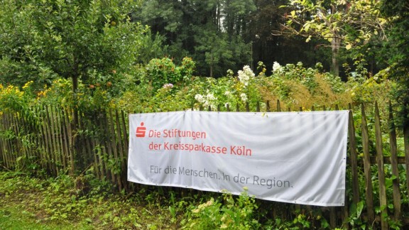 Das Banner der Stiftungen der Kreispparkasse hängt am Zaun des Bauerngartens