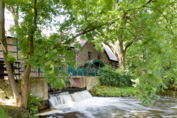 Das Bild zeigt die Sindorfer Mühle mit ihrem grünen Wasserrad.